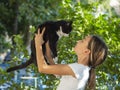 Teenager girl holds a black stray cat in her arms and looks at him. Royalty Free Stock Photo