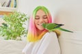 Teenager girl kissing a parrot. Close-up face of woman and green quaker parrot