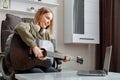 Teenager girl learning play guitar at home using online lessons. Hobby remote musical education acoustic guitar. Young woman play