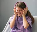 A teenager girl in a lilac T-shirt in pink headphones listens to audio music, emotions of teenager.