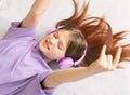 A teenager girl in a lilac T-shirt in pink headphones listens to audio music, emotions of teenager