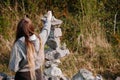 Teenager girl with long hair finishing building very complicated balance stone tower. Selective focus. Patience and internal zen Royalty Free Stock Photo