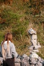 Teenager girl with long hair finishing building very complicated balance stone tower. Selective focus. Patience and internal zen Royalty Free Stock Photo