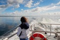 Teenager girl looking at the ocean from a deck of a cruise ship. Galway bay, Ireland. The model back to viewer. Blue cloudy sky. Royalty Free Stock Photo