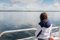 Teenager girl looking at the ocean from a deck of a ferry ship. Galway bay, Ireland. The model back to viewer. Blue cloudy sky.