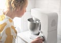 teenager girl looking at planetary mixer bowl with whipping cream. side view of a girl making whipped icing for cake Royalty Free Stock Photo