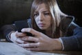 Teenager girl looking worried and desperate to mobile phone as internet stalked victim abused cyberbullying stress Royalty Free Stock Photo