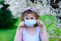 Teenager girl in medical mask in spring flowering garden