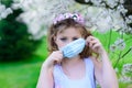 Teenager girl in medical mask in spring flowering garden