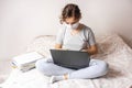 Teenager girl with medical mask is studying online on her bed. Homework on lap top Royalty Free Stock Photo