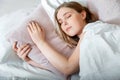 Teenager girl in pajamas sleeps in bedroom at morning time. Young Woman sleeping in bed. Portrait of blonde teen girl Royalty Free Stock Photo