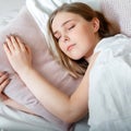 Teenager girl in pajamas sleeps in bedroom at morning time. Young Woman sleeping in bed. Portrait of blonde teen girl Royalty Free Stock Photo