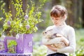 Teenager girl  play with real rabbit in the garden. Smiling child at Easter egg hunt with  pet bunny. Spring outdoor fun for kids Royalty Free Stock Photo