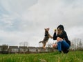 Teenager girl playing with cute Yorkshire terrier in a park on a green grass field. Day time. Cloudy sky. Model dressed in black Royalty Free Stock Photo