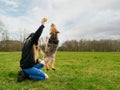 Teenager girl playing with cute Yorkshire terrier in a park on a green grass field. Day time. Cloudy sky. Model dressed in black Royalty Free Stock Photo