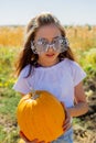 Teenager girl and pumpkin in the vegetable garden. A girl with a pumpkin in her hands wearing glasses for Halloween Royalty Free Stock Photo