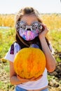 Teenager girl and pumpkin in the vegetable garden. halloween and girl in protective mask. Teenager girl and pumpkin Royalty Free Stock Photo