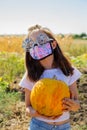 Teenager girl and pumpkin in the vegetable garden. halloween and girl in protective mask. Teenager girl and pumpkin Royalty Free Stock Photo