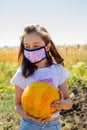 Teenager girl and pumpkin in the vegetable garden. halloween and girl in protective mask. Teenager girl and pumpkin Royalty Free Stock Photo