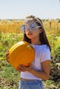 Teenager girl and pumpkin in the vegetable garden. A girl with a pumpkin in her hands wearing glasses for Halloween Royalty Free Stock Photo