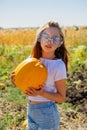 Teenager girl and pumpkin in the vegetable garden. A girl with a pumpkin in her hands wearing glasses for Halloween Royalty Free Stock Photo