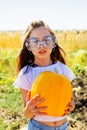 Teenager girl and pumpkin in the vegetable garden. A girl with a pumpkin in her hands wearing glasses for Halloween Royalty Free Stock Photo