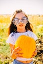 Teenager girl and pumpkin in the vegetable garden. A girl with a pumpkin in her hands wearing glasses for Halloween Royalty Free Stock Photo