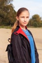 Teenager girl in a raincoat and backpack walk outdoors