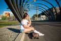 Teenager girl rest on sidewalk and drink water after ride on longboard