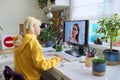 Teenager girl sitting at home studying online using home computer.