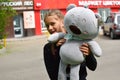 Teenager girl with soft cute toy near the store rejoices.