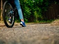 Teenager girl standing with her foot and bike on a path into dark scary forest. Concept risk evaluation, scary unknown, adventure Royalty Free Stock Photo