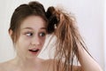 Teenager girl in surprise looks at matted hair. Royalty Free Stock Photo