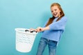 Teenager girl throw her glasses in the trash and smiles,  on blue background Royalty Free Stock Photo