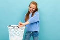 Teenager girl throw her glasses in the trash and smiles, isolated on blue background Royalty Free Stock Photo