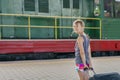 Teenager girl at the train station near the locomotive. girl pulling a large suitcase on the platform Royalty Free Stock Photo