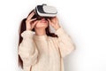 Young girl with two ponytails in virtual reality headset studio standing isolated on white watching video cheerful