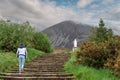 Teenager girl walking on a stair way to Croagh Patrick, county Mayo, Ireland. Cloudy sky. Mountain peak and white statue in the Royalty Free Stock Photo