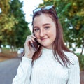 Teenager girl, white sweater, summer city. Calls smartphone, listens to voice message. Happy smiling having fun and Royalty Free Stock Photo