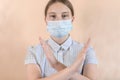 Teenager girl 12-15 years old, in medical mask covers her face, cross hand gesture, stop passage closed, attention