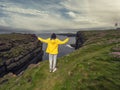 Teenager girl in yellow jacket on edge of stunning cliff in county Clare, Ireland, Loop head area. Dramatic cloudy sky. Irish Royalty Free Stock Photo