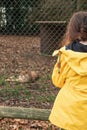 Teenager girl in yellow jacket looking at sleeping cheetah in a zoo. Learning nature concept. Kid study predator