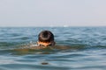 Teenager in goggles swims in the sea with big splashes. Cute boy enjoys swimming in the ocean. Royalty Free Stock Photo