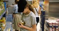 Teenager in grocery store or supermarket hold glass jar of olive and read label Royalty Free Stock Photo