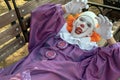 A teenager guy in a clown costume with sharp teeth lies on a bench. Street make-up, Halloween cosplay or a horror character Royalty Free Stock Photo