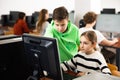 Teenager guy helps girl solve problem on computer in school class