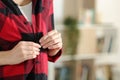 Teenager hand fastening button of red shirt at home