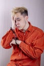 A teenager in handcuffs holds his head with his hands on a gray background. Headache for juvenile delinquents in quarantine, Royalty Free Stock Photo