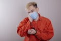 A teenager in handcuffs and a medical mask holds his head against a gray background.Headache for juvenile delinquents in quarantin Royalty Free Stock Photo