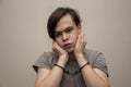 A teenager in handcuffs sits on a gray background, medium plan. Juvenile delinquent, criminal liability of minors.